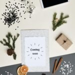 Overhead view of a holiday-themed flatlay featuring a 'Coming soon' card, tablet, and decorations.