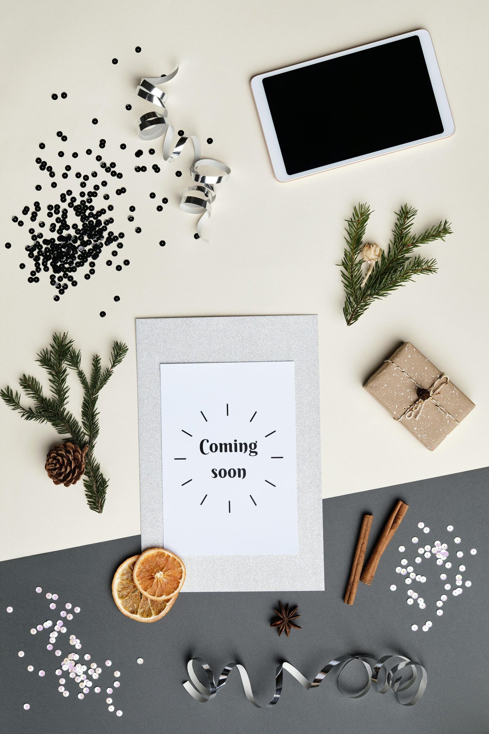 Overhead view of a holiday-themed flatlay featuring a 'Coming soon' card, tablet, and decorations.